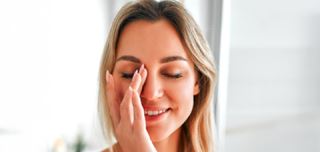 Woman touching her eye while experiencing discomfort from dry eye syndrome
