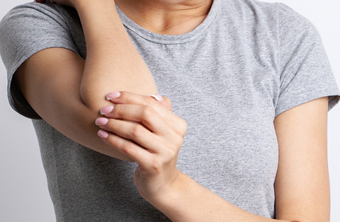 Woman holding arm with nerve discomfort, illustrating need for brachial plexus surgery and nerve repair in Turkey