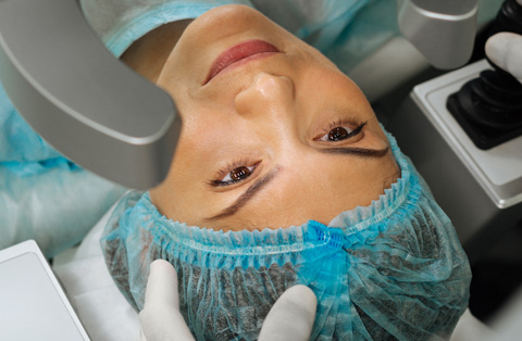 Close-up of a woman undergoing cornea transplant surgery in Turkey, with medical equipment and surgical cap visible.