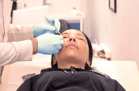 Doctor performing post-op check on female patient after cosmetic facial surgery