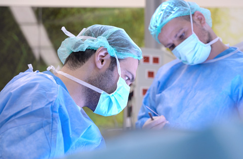 Two surgeons in sterile gowns performing general surgery in operating room