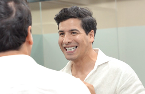 Male dental patient smiling at his reflection after cosmetic dental treatment