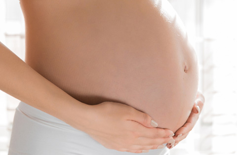 Pregnant woman holding her belly after successful IVF treatment in Turkey, symbolizing fertility journey and care