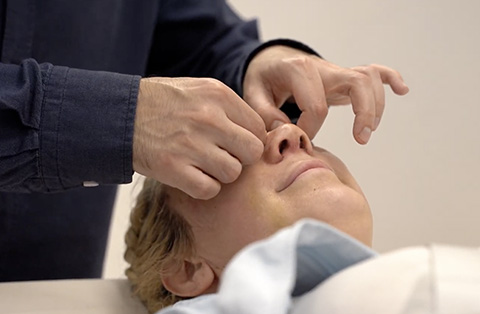 a post-rhinoplasty check-up with hands carefully adjust the patients nose