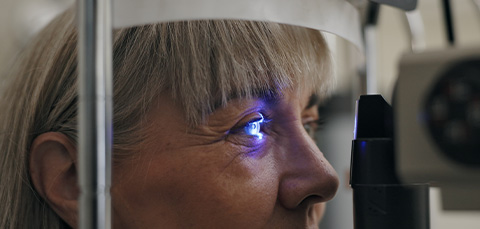 Senior woman having an eye exam with a blue light to check for cataracts affecting night vision