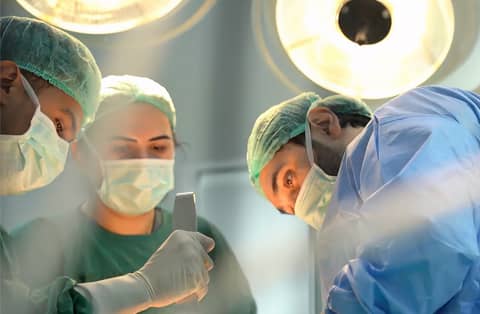 Masked surgical team performing reconstructive procedure under bright operating-room lights.
