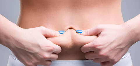 Woman pinching loose abdominal skin illustrating tummy tuck with muscle repair and abdominal tightening procedure
