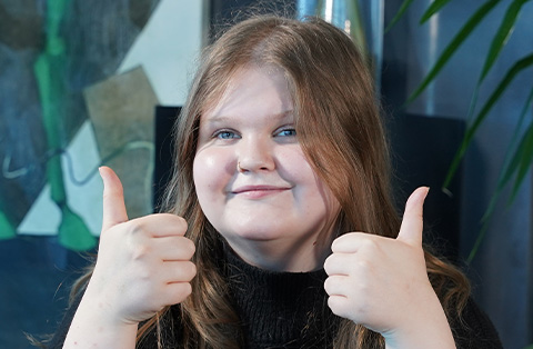 Smiling woman giving thumbs up after successful weight loss surgery