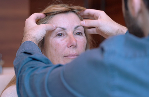 Surgeon evaluating female patients forehead and brow area for temporal lift procedure