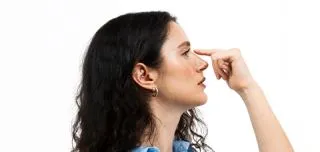 Woman touching her nose, illustrating augmentation rhinoplasty for improved nose shape and facial profile