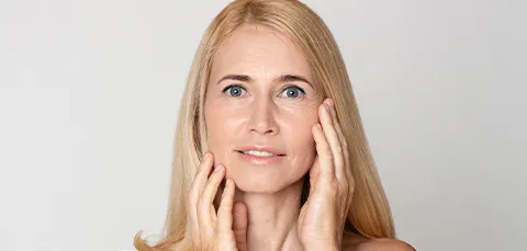 Middle-aged woman touching her rejuvenated face after endoscopic facelift in Turkey