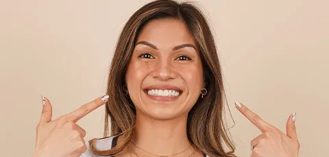 Woman smiling and pointing at her gum area, possibly indicating a dental fistula